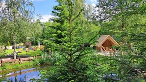 Eine Holzjagdhaus umgeben von üppiger Vegetation und einem Teich.