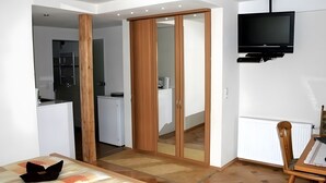 Ein modernes Zimmer mit einem Holzschrank, einem an der Wand befestigten Fernseher und einem Essbereich mit Tisch und Stühlen.