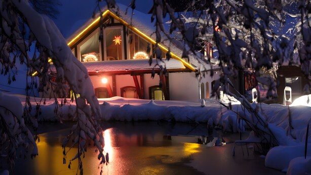 A snow-covered building with a lit interior, a snow-covered ground, and a reflective water surface. - Holiday Apartment for 2 People (60 m²) in Sehmatal (Sehmatal)