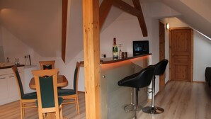 A compact kitchen with a dining area, wooden beams, a small refrigerator, and a TV on the wall. - Holiday Apartment for 2 People (60 m²) in Sehmatal (Sehmatal)