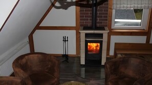 Une pièce chaleureuse avec une cheminée, des poutres en bois et une fenêtre offrant une belle vue.