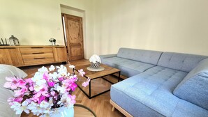 A living room with a sofa, a coffee table, a wooden cabinet, and a vase with flowers. - Adorable 2-bedroom apartment  - TGM 2 (Český Krumlov)