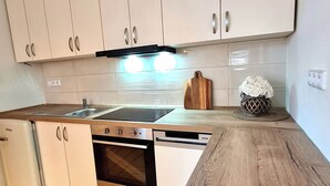 A modern kitchen with white cabinets, a wooden countertop, a built-in oven, and a sink. - Adorable 2-bedroom apartment  - TGM 2 (Český Krumlov)