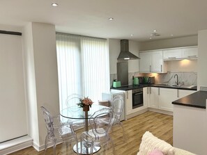 A modern kitchen with white cabinets, a black countertop, and a stainless steel range hood. - The Beverly Walton Apartment (Bedford)