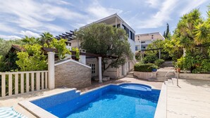 A swimming pool with a stone border, a pergola, and a staircase leading to a building. - Luxury Garden Villa 50m from the Beach (Sutivan)