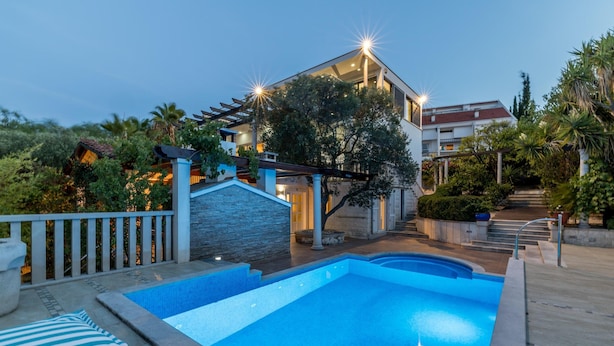 A residential property with a swimming pool, stone walls, and a well-lit entrance. - Luxury Garden Villa 50m from the Beach (Sutivan)