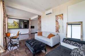 A modern living room with a sofa, ottoman, and a workout station. - Luxury Garden Villa 50m from the Beach (Sutivan)