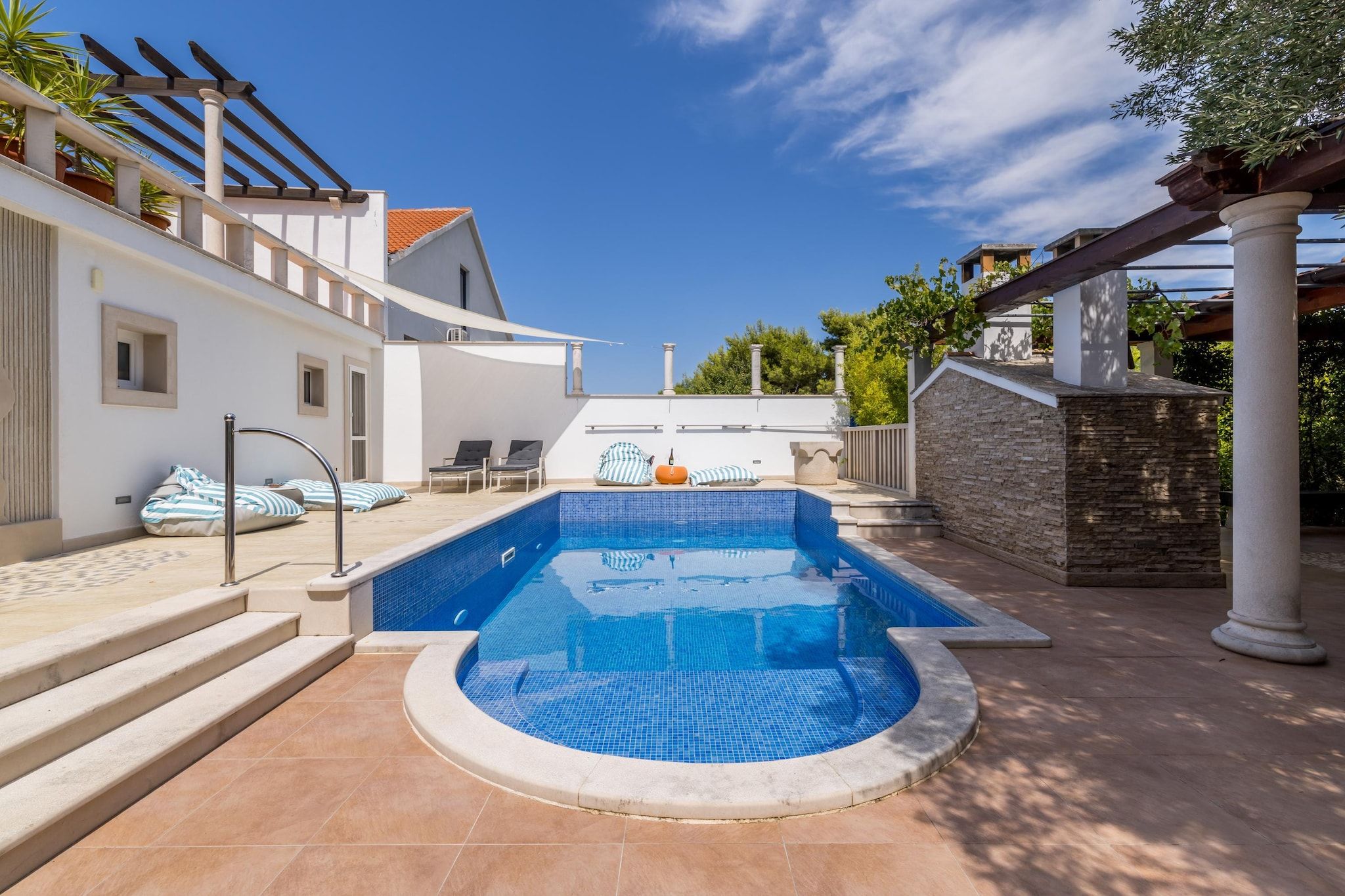 Piscina com borda azulejada, ladeada por degraus que levam a um terraço.