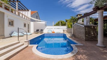 Piscina com borda azulejada, ladeada por degraus que levam a um terraço.