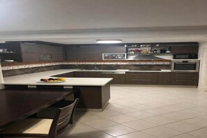 Una cocina moderna con armarios oscuros, una isla central y piso de baldosas.