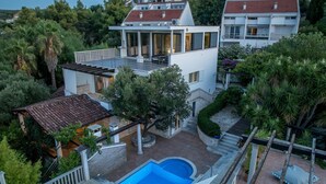 A residential property with a swimming pool, multiple balconies, and surrounding greenery. - Luxury Garden Villa 50m from the Beach (Sutivan)