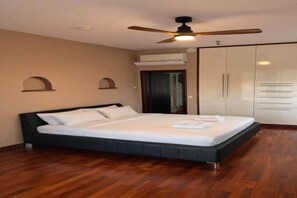 Un dormitorio con cama, ventilador de techo, aire acondicionado y armario.
