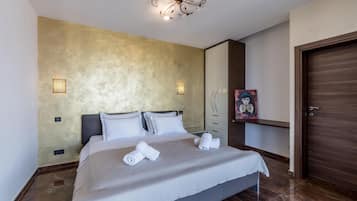 Una habitación de hotel con una cama, una lámpara de pared, una puerta y un cuadro en la pared.