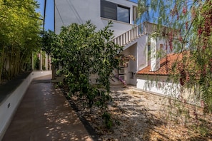 A pathway leading to a modern building with a staircase and a garden area with various plants. - Luxury Garden Villa 50m from the Beach (Sutivan)