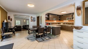 A modern kitchen with a central island, dark cabinetry, and a tiled backsplash. - Luxury Garden Villa 50m from the Beach (Sutivan)