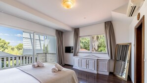 A spacious bedroom with a large bed, a built-in TV, and a balcony with a view of greenery. - Luxury Garden Villa 50m from the Beach (Sutivan)