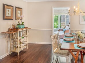 A dining area with a wooden table set for four, a wicker sideboard, and a chandelier. - Charming 5-bedroom house, block and a half to the beach in Bay Head (Bay Head)