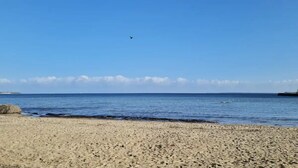 Une plage avec un ciel dégagé, un rivage sablonneux et une île lointaine.