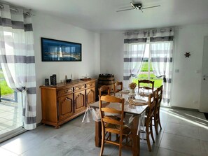 A dining area with a wooden table, chairs, a cabinet, and a view of greenery outside.