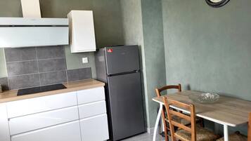Une cuisine équipée d’un réfrigérateur, d’une table à manger avec des chaises et d’une horloge murale.