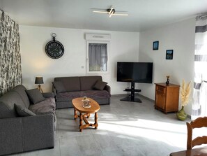 A living room with a sofa, a coffee table, a TV, and a clock on the wall.