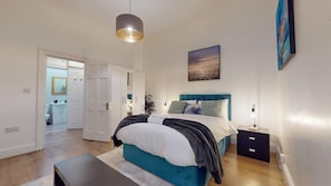Ein Schlafzimmer mit einem Bett, einem Nachttisch, einer Lampe und einem Bild an der Wand.