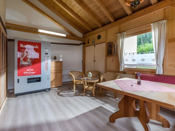 Ein Holzblockhaus-Interieur mit einem Tisch, Stühlen, einer Minibar und einem Fenster mit Blick.