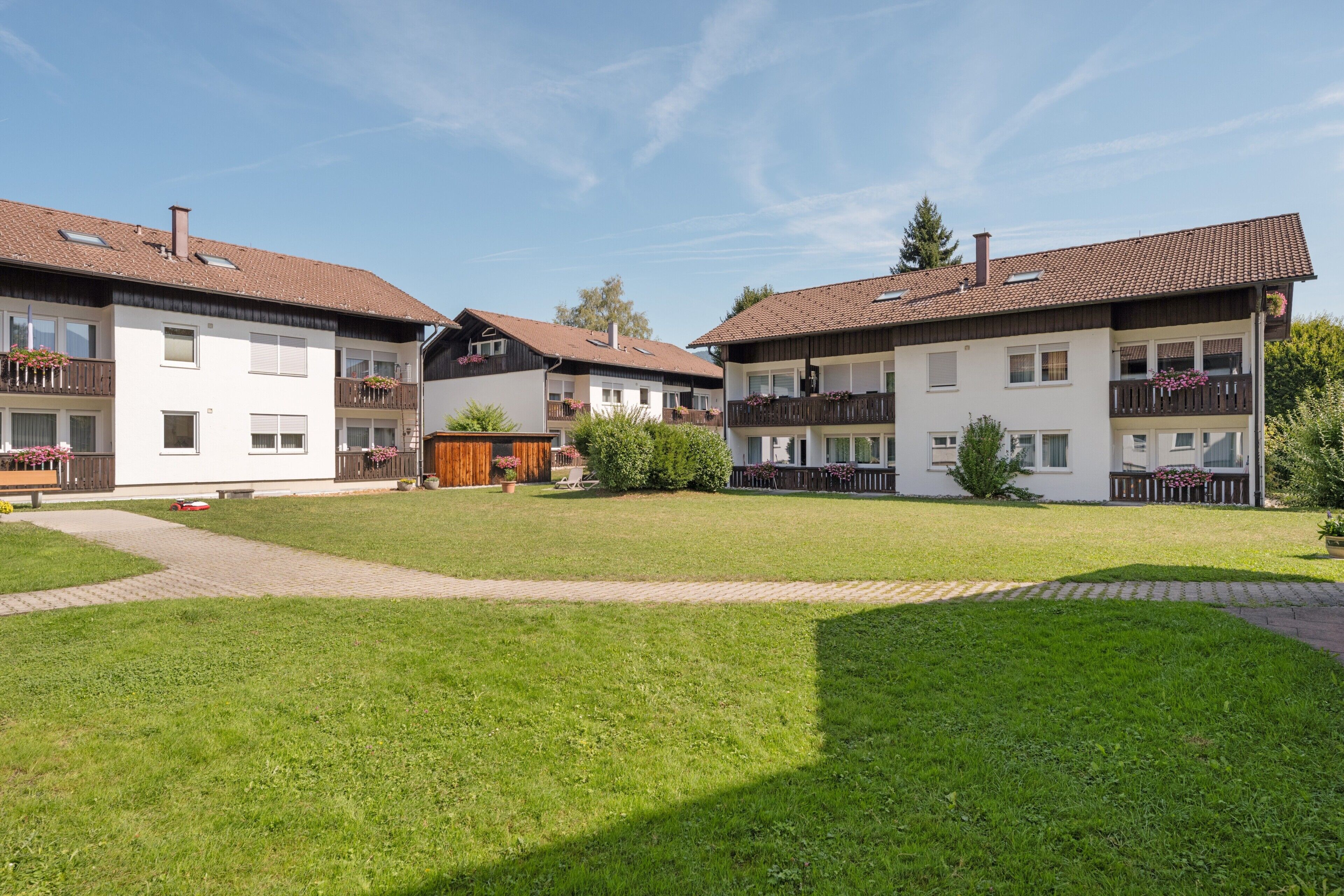Ein Wohngebäude mit Innenhof, mehreren Balkonen und blauem Himmel.