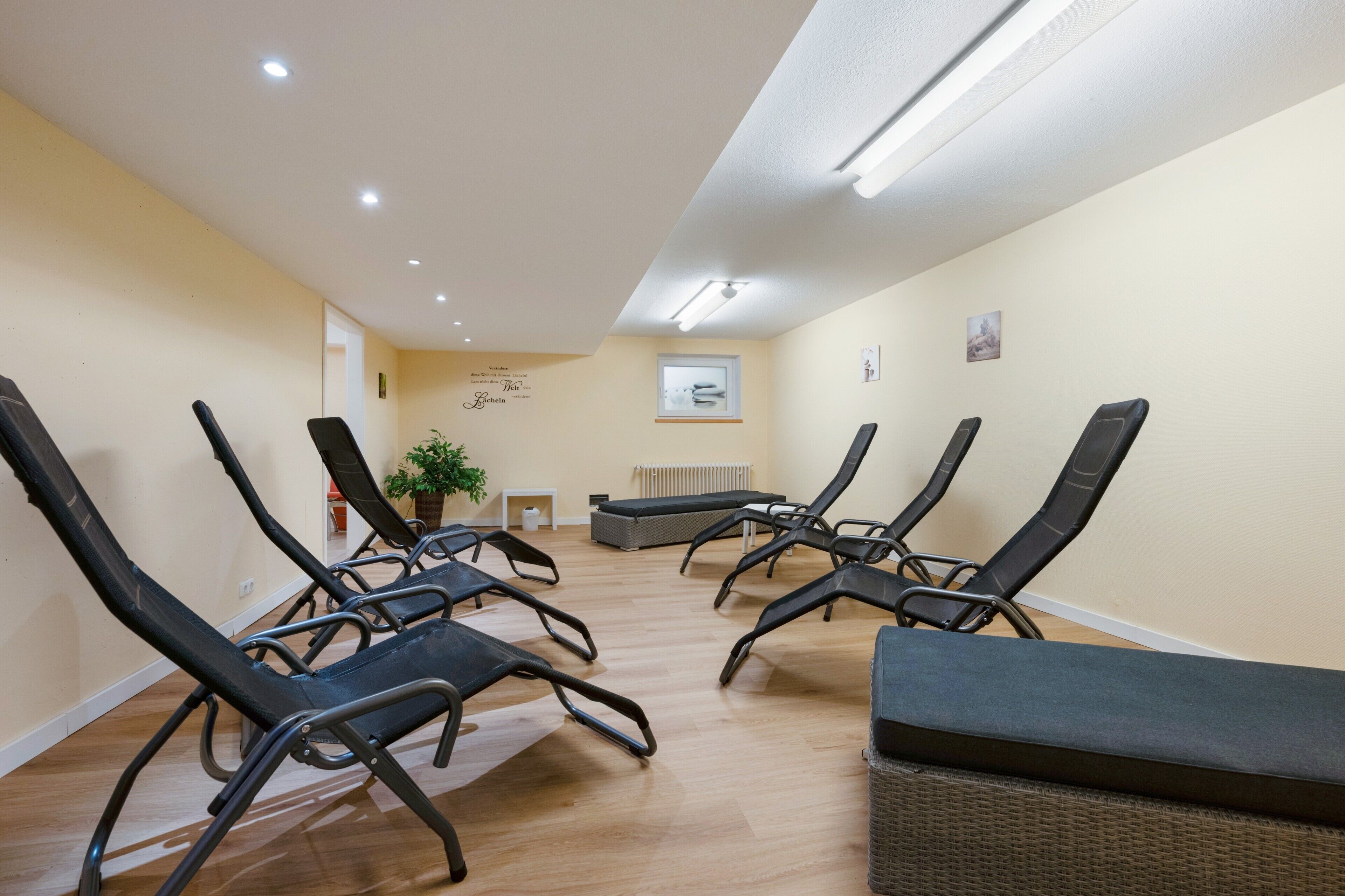 Una habitación con sillones reclinables, una mesita y una planta en maceta.