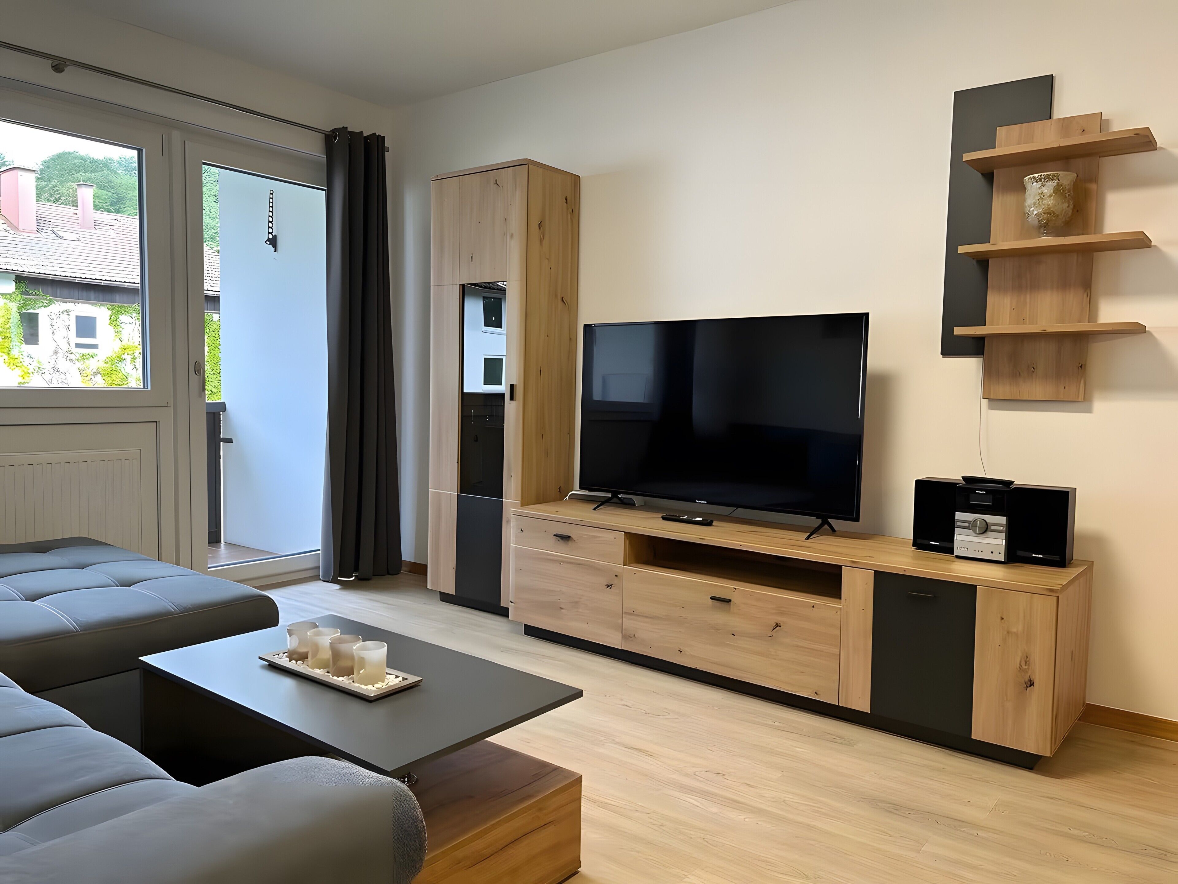 Ein modernes Wohnzimmer mit einem großen Flachbildfernseher, einer Couch und einem Couchtisch.