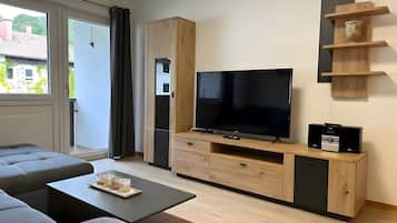 Ein modernes Wohnzimmer mit einem großen Flachbildfernseher, einer Couch und einem Couchtisch.