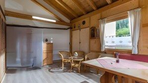 Un interior de madera con una mesa, sillas y un ventanal con cortinas.