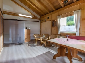 A wooden interior with a table, chairs, and a window with curtains.
