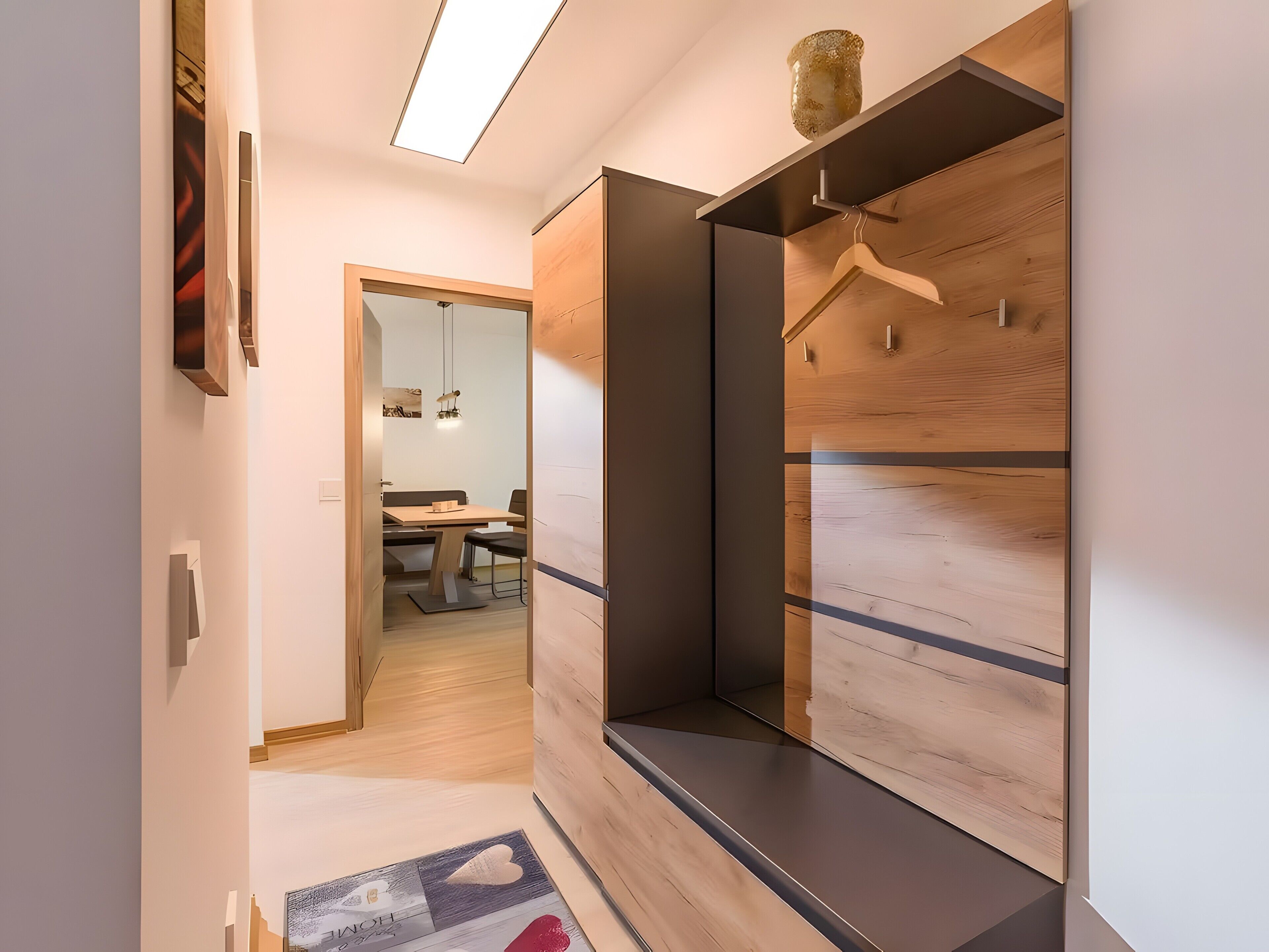 Ein modernes Interieur mit einem Holzschrank, einem Spiegel und einem Essbereich im Hintergrund.