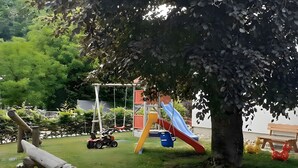 Un parque infantil con columpios, toboganes y un coche de juguete.