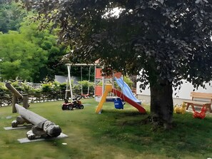 A playground with a swing set, slides, and a toy car.