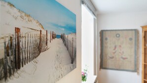 Een gang met een strandschilderij, een wandtapijt en een raam met uitzicht.