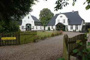 A traditional white building with a gravel driveway and a wooden gate. - Apartment 'Ferien Auf Dem Lande' with Shared Garden, Balcony and Wi-Fi (Scheggerott)