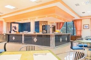A hotel lobby with a central bar, seating area, and a view of the outdoors. - Checkin Basic León Norte (Villaquilambre)