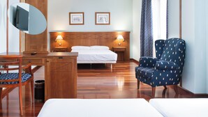 Ein Hotelzimmer mit einem Bett, einem Schreibtisch, einem Sessel, einem Fernseher und zwei Nachttischlampen.