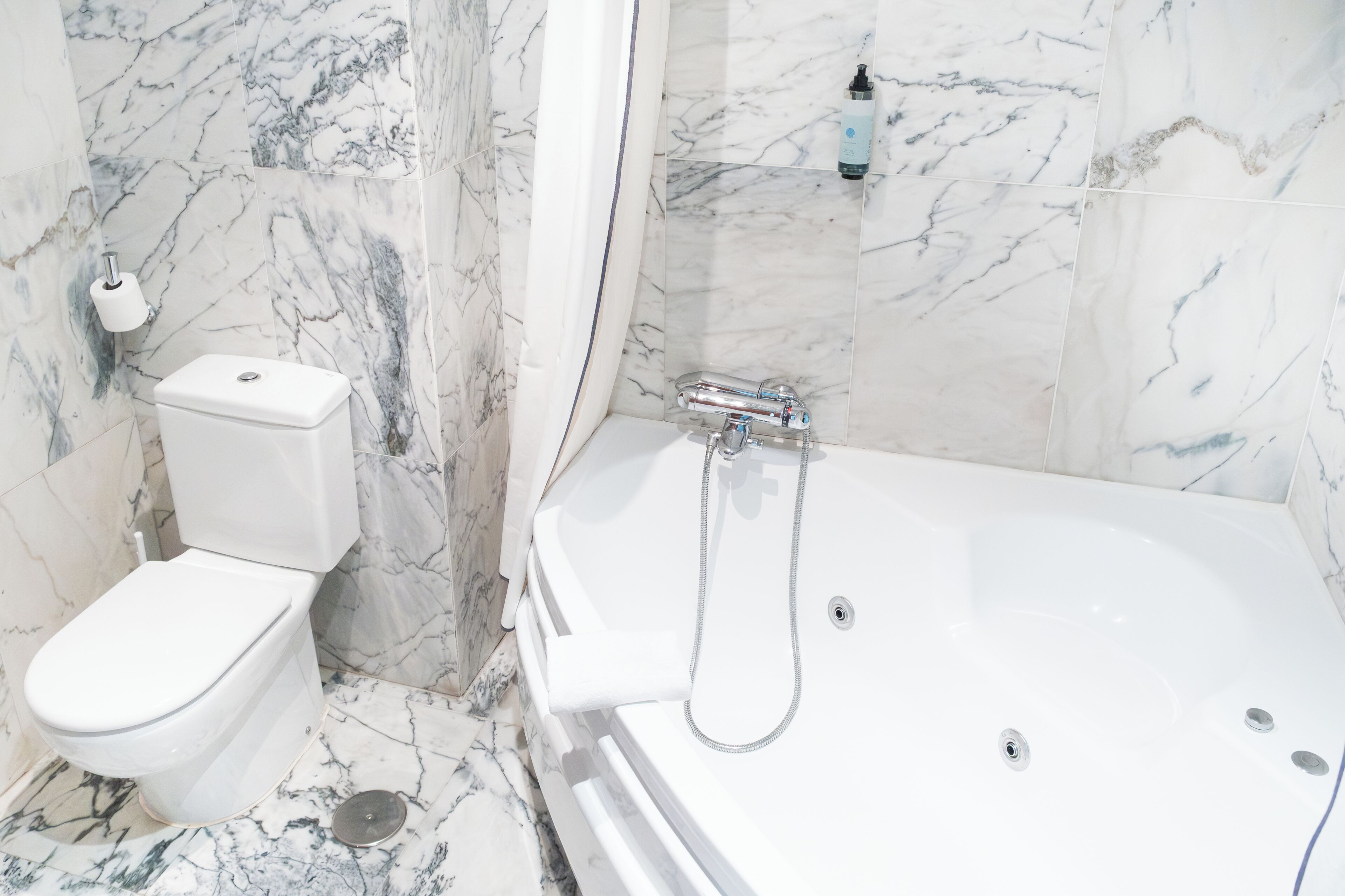 Ein Badezimmer mit Toilette, Badewanne und Marmorwänden.