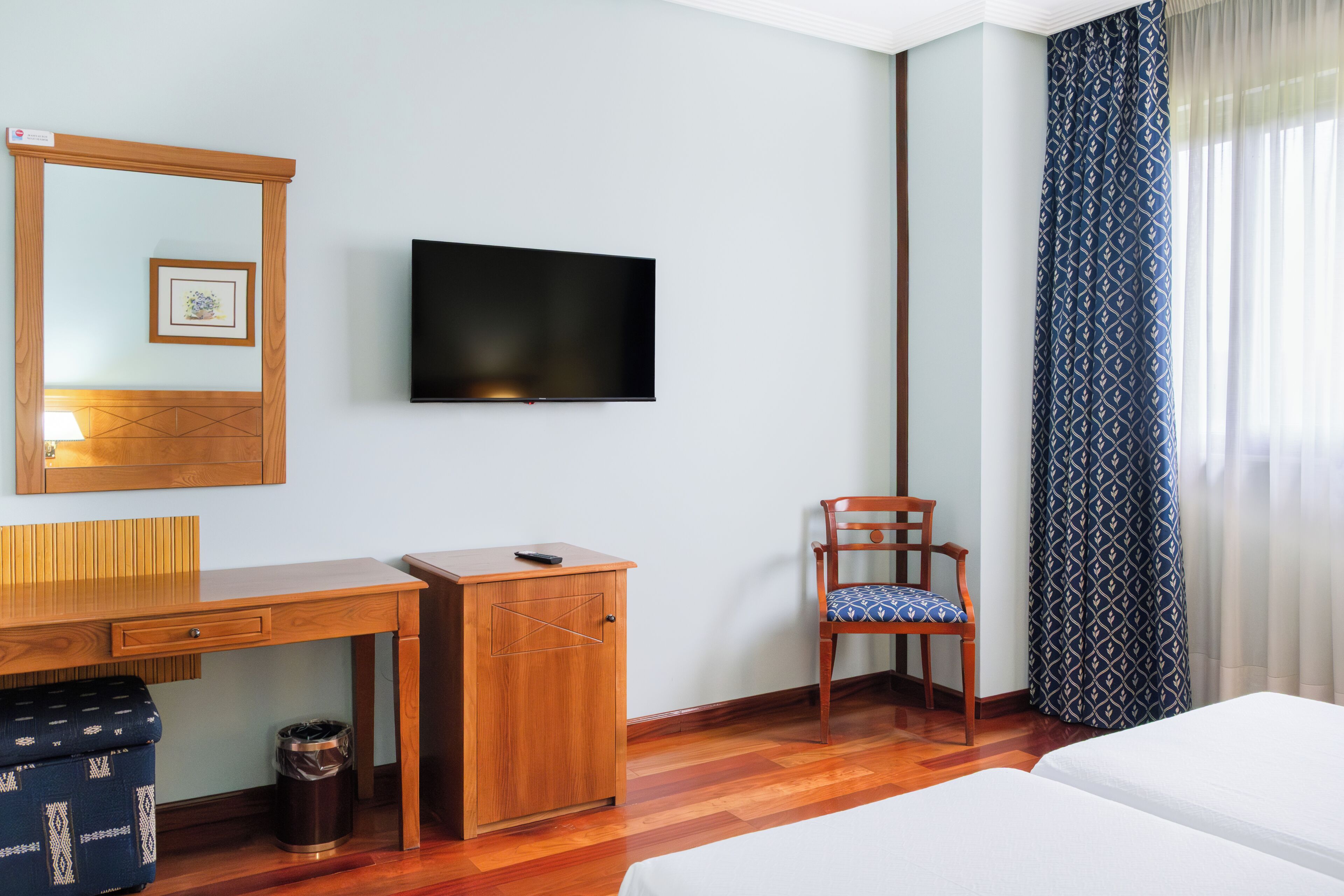Habitación de hotel con escritorio de madera, televisor, silla y cama.