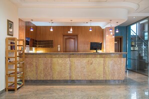 A reception desk with a marble counter, wooden paneling, and pendant lighting. - Checkin Basic León Norte (Villaquilambre)