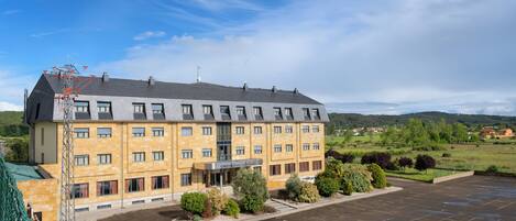 A multi-story hotel with a parking lot and a view of the surrounding landscape.