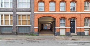 A multi-story building with a brick facade, a central archway entrance, and a black door marked with the number 58. - 3BR Contractor Pad | Free Private Parking | WiFi (West Midlands)
