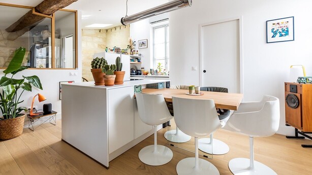 A modern kitchen with white cabinetry, a wooden island, and a dining area with white chairs. - La Pomme des Chartrons – Apartment in Bordeaux, Wi-Fi & Air Conditioning (Bordeaux)