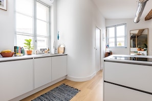 Una cocina moderna con armarios blancos, horno integrado y ventana con persianas.