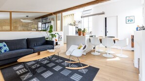 A modern living room with a sofa, coffee table, and a dining area with chairs and a table. - La Pomme des Chartrons – Apartment in Bordeaux, Wi-Fi & Air Conditioning (Bordeaux)