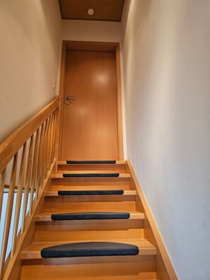 A wooden staircase with black non-slip treads leading to a closed door. - Apartment 'Herdi-Schön' with Balcony (Herdwangen-Schönach)