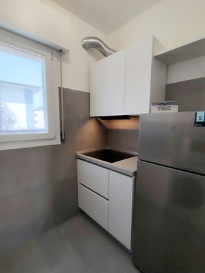 Eine kompakte Küche mit eingebautem Herd, einem Kühlschrank und einem Stauraumschrank.
